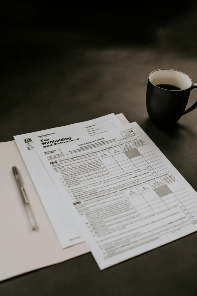 Documento com tabela e texto financeiro impresso sobre uma mesa escura, ao lado de uma caneta e de uma xícara de café preta ao fundo desfocado, estilo corporativo.